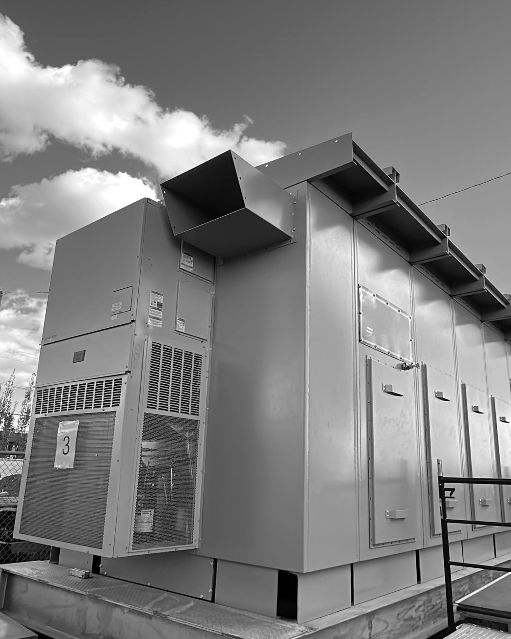 Outdoor switchgear enclosure with drip-hood roof and integrated HVAC on a galvanized structural steel skid